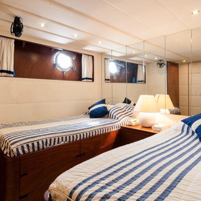 Twin beds in a luxurious Codecasa 26m yacht cabin, featuring striped bedding and elegant decor.