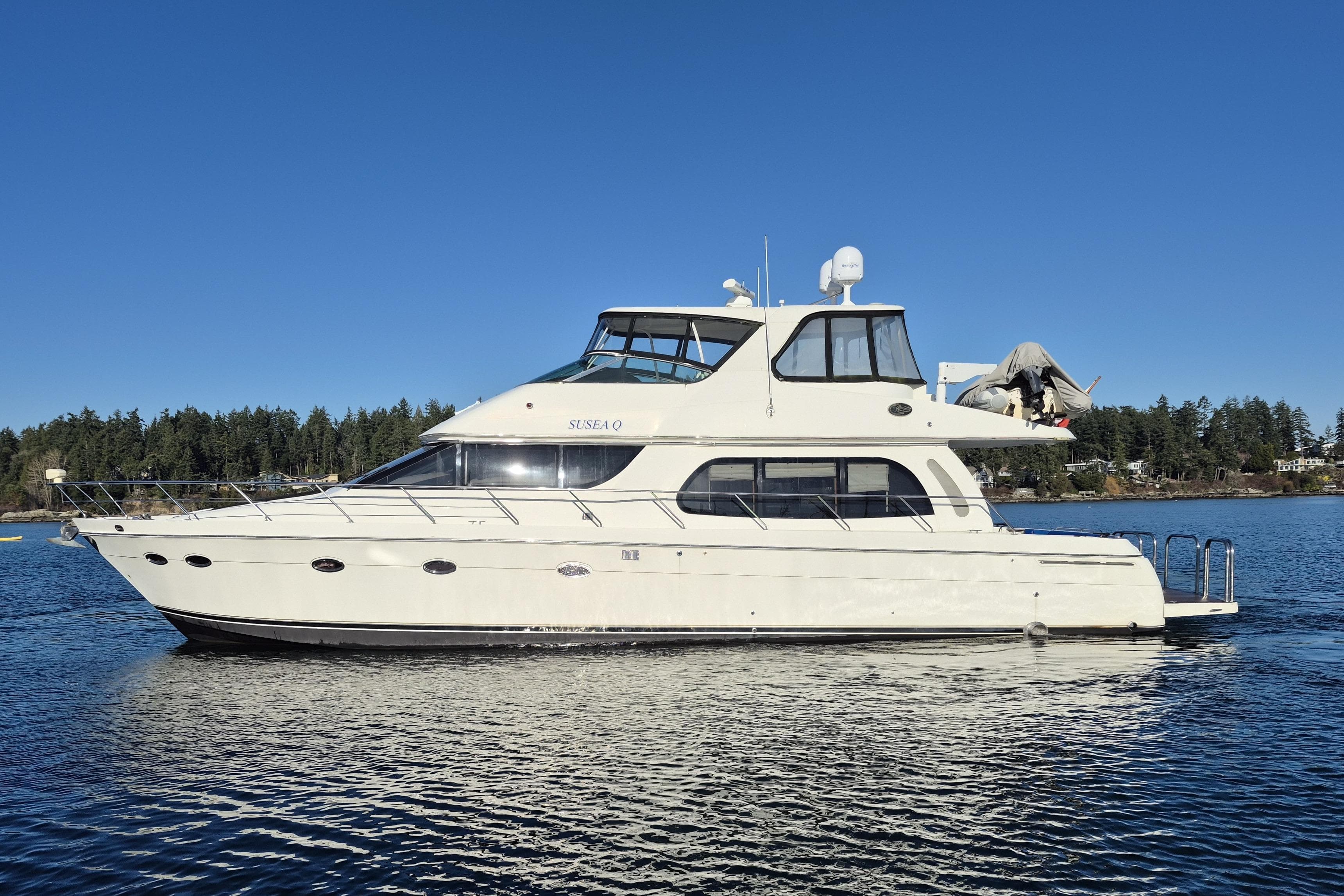 2005 Carver 560 Voyager yacht on calm water under clear blue sky.
