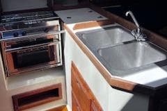 1984 Catalina 36 Tall Rig yacht kitchen with stove, sink, and wooden cabinetry.