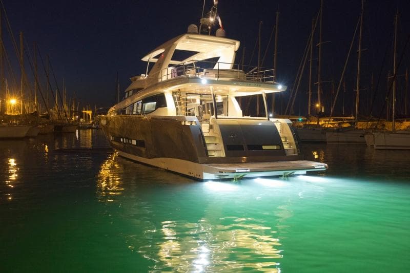 Prestige 750 yacht, 2016 model, illuminated at night in a marina.