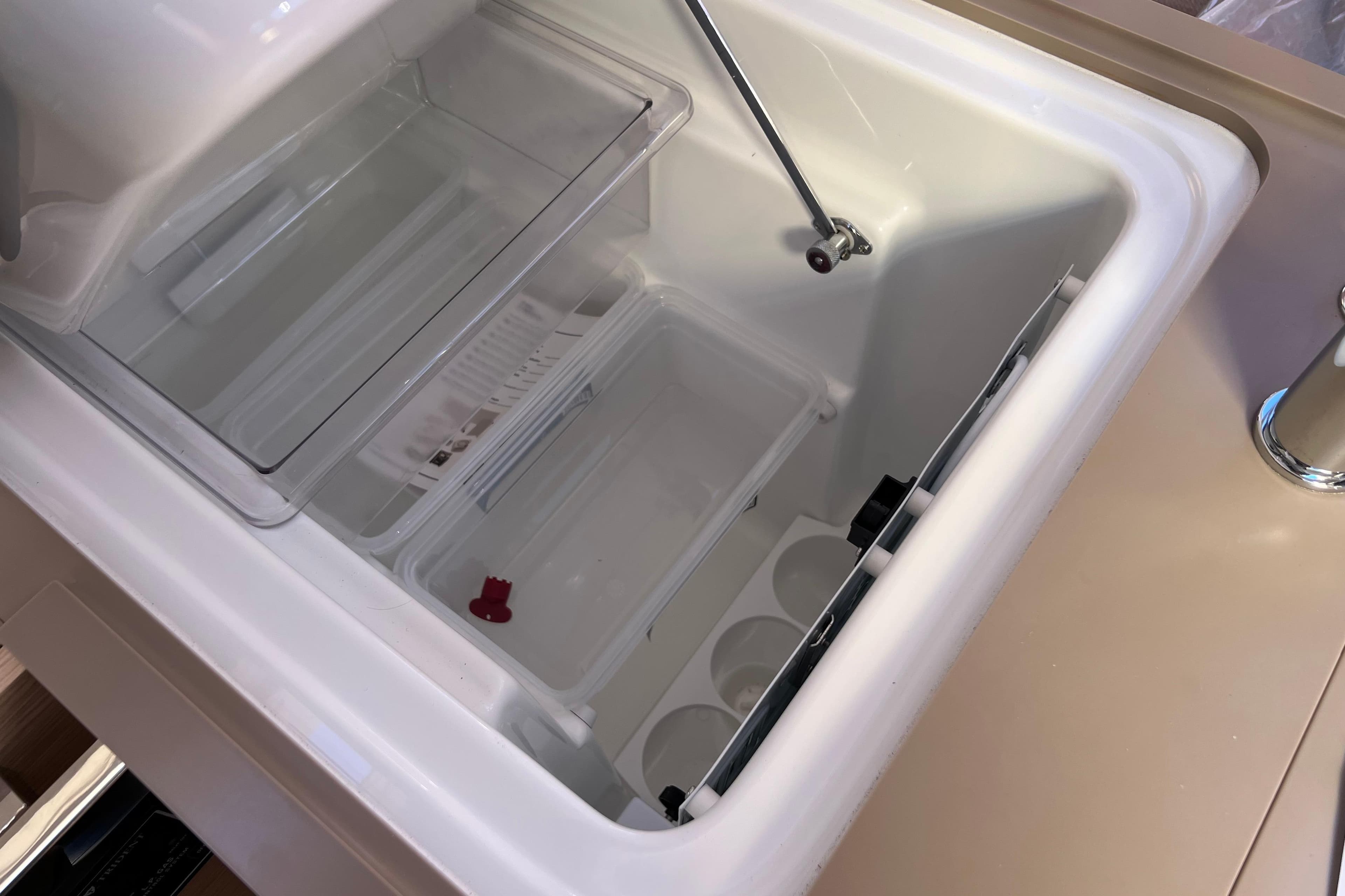 2026 Dufour 37 yacht interior fridge with open lid and storage compartments.