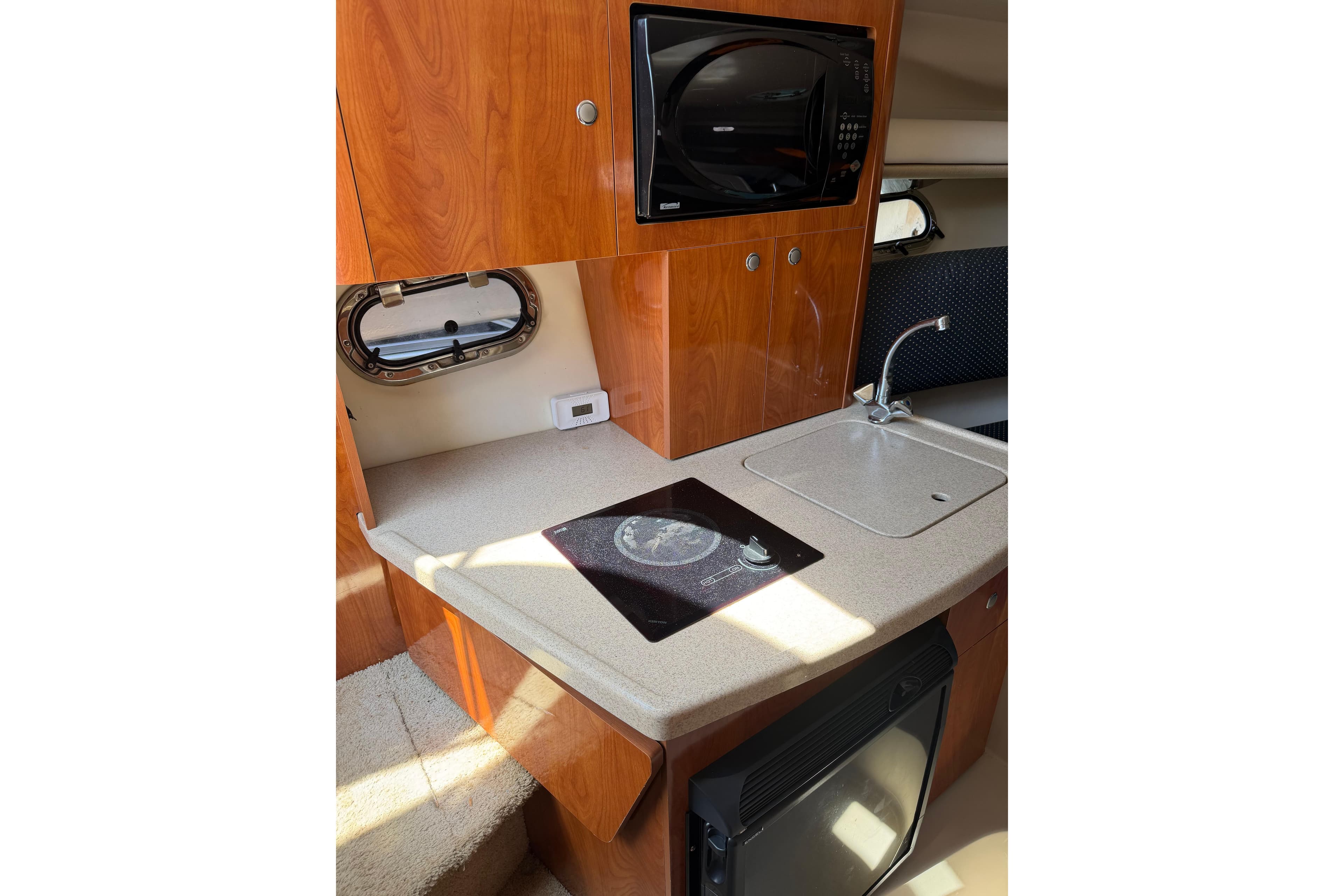 Compact kitchen area in 2004 Four Winns 268 Vista boat with sink and microwave.