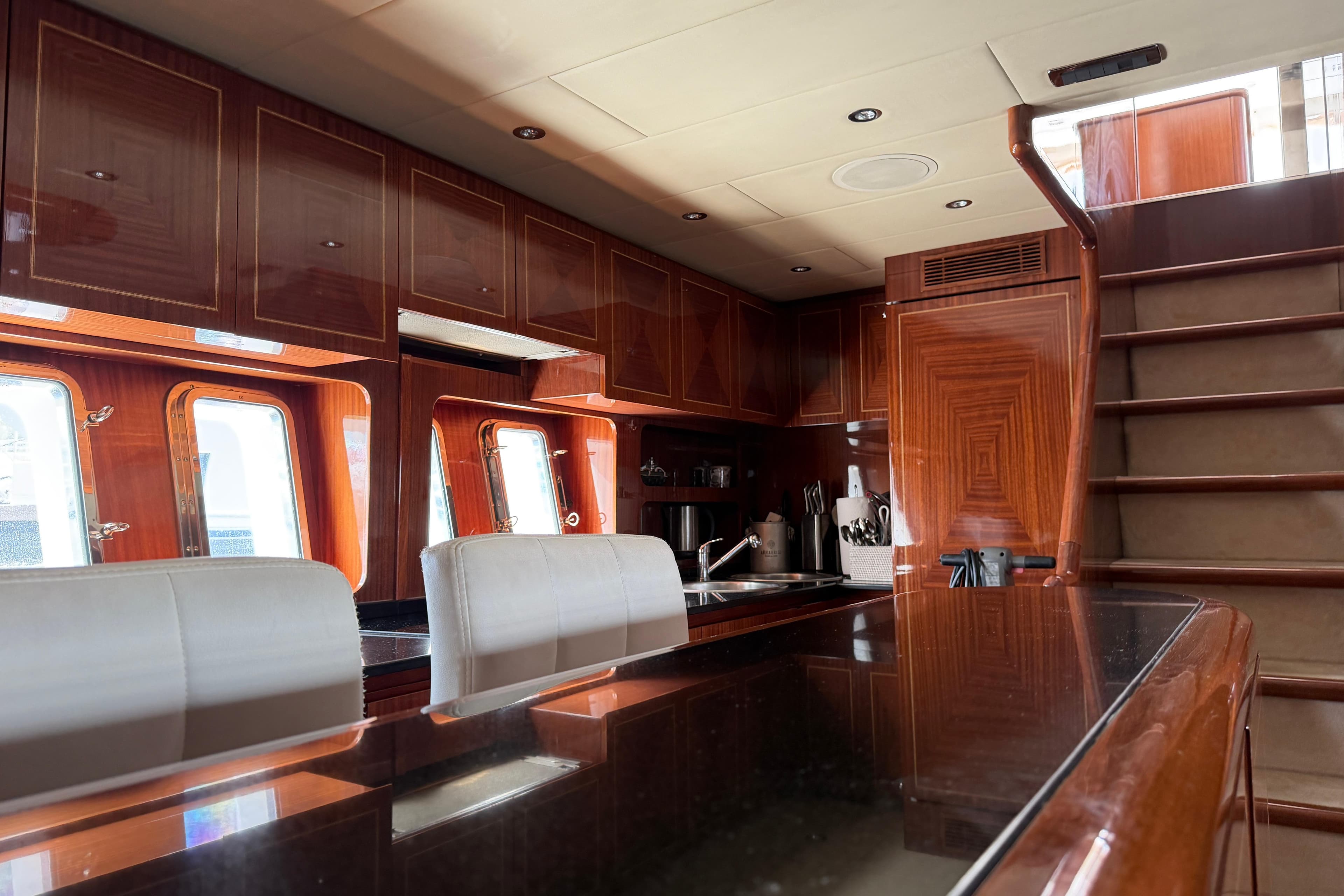 Luxurious interior of 2004 Mangusta 72 yacht with polished wood and modern kitchen.