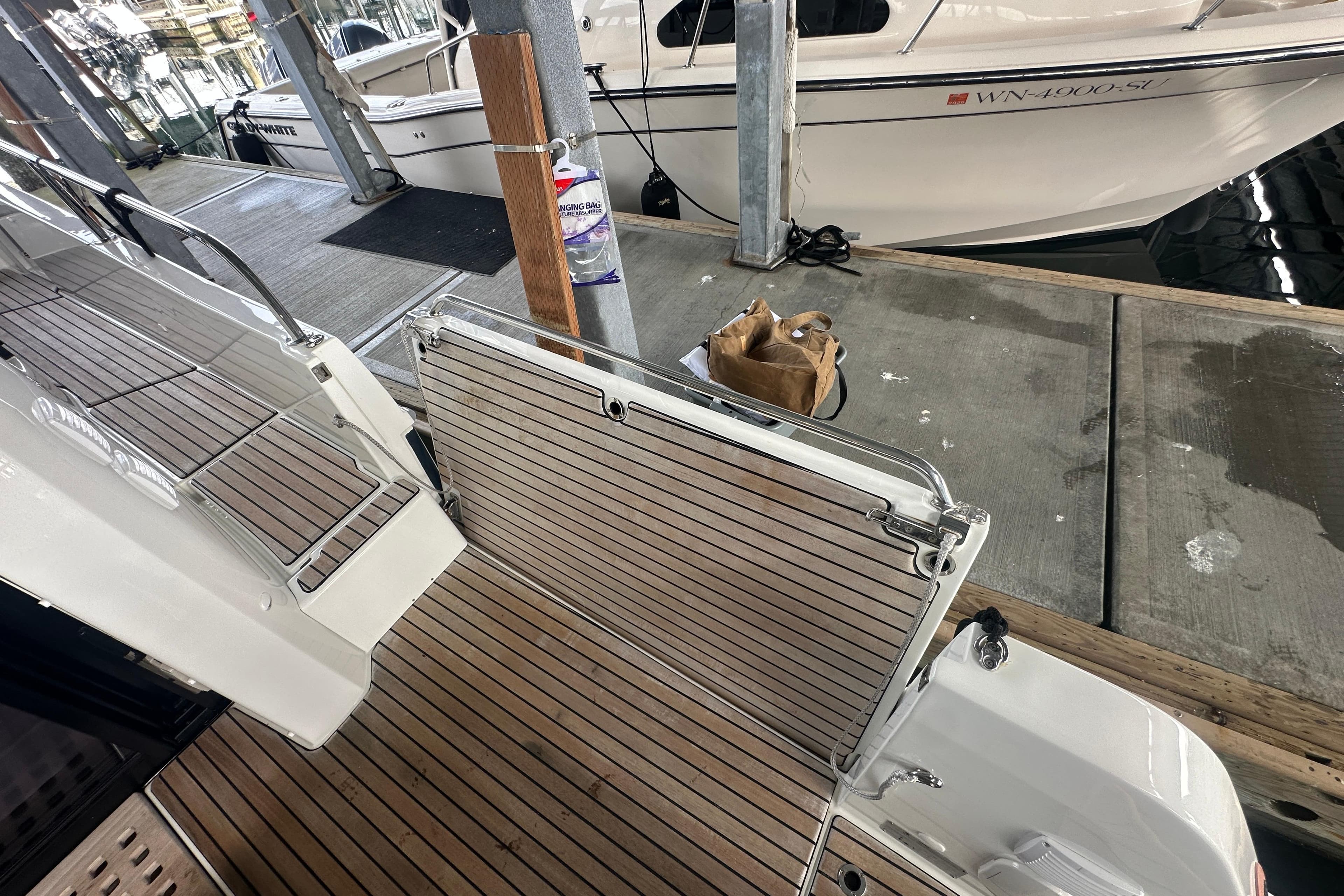 2023 Beneteau Antares 11 Coupe docked, showcasing teak deck and boarding gate.