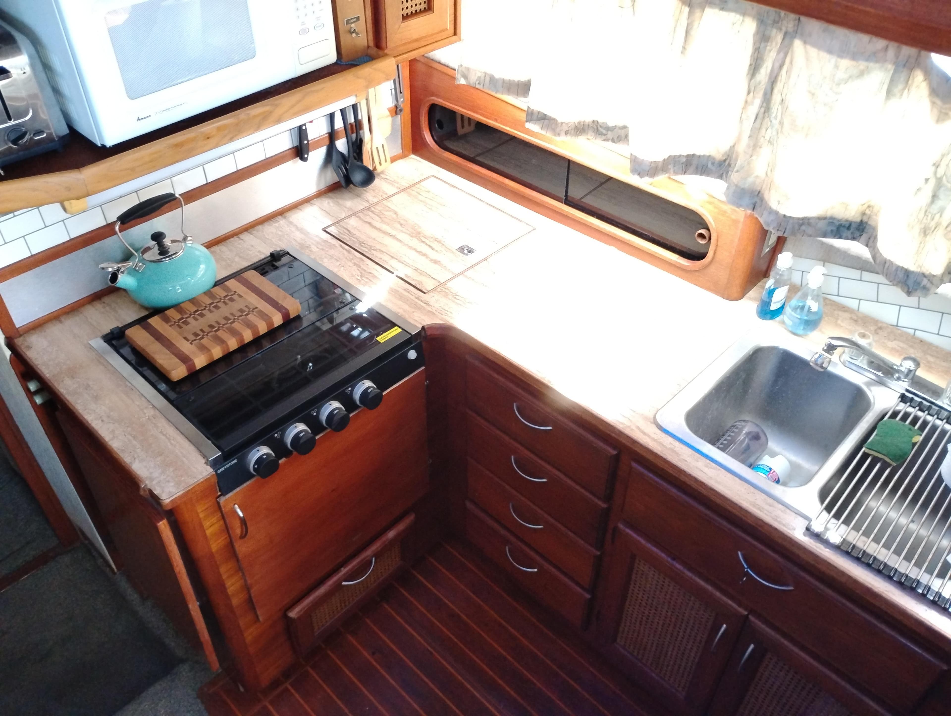 1986 Bayliner 3870 Motoryacht kitchen with stove, sink, and wooden cabinetry.
