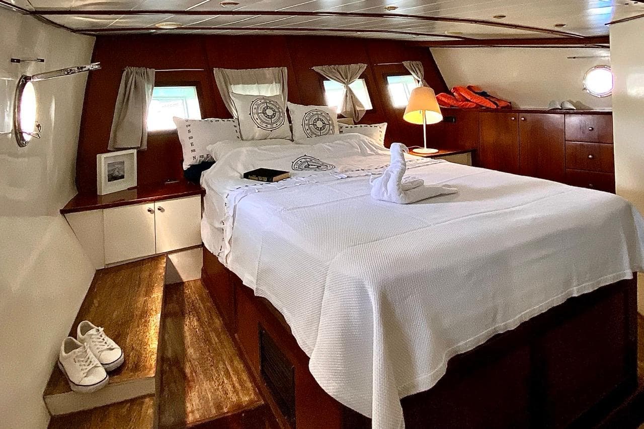 Luxurious cabin interior of 2002 Custom Gulet Motorsailer with cozy bed and elegant decor.