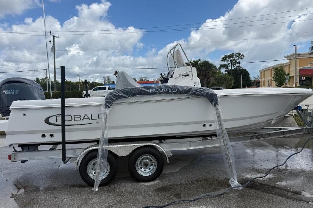 2026 Robalo 226 Cayman boat on trailer under cloudy sky.