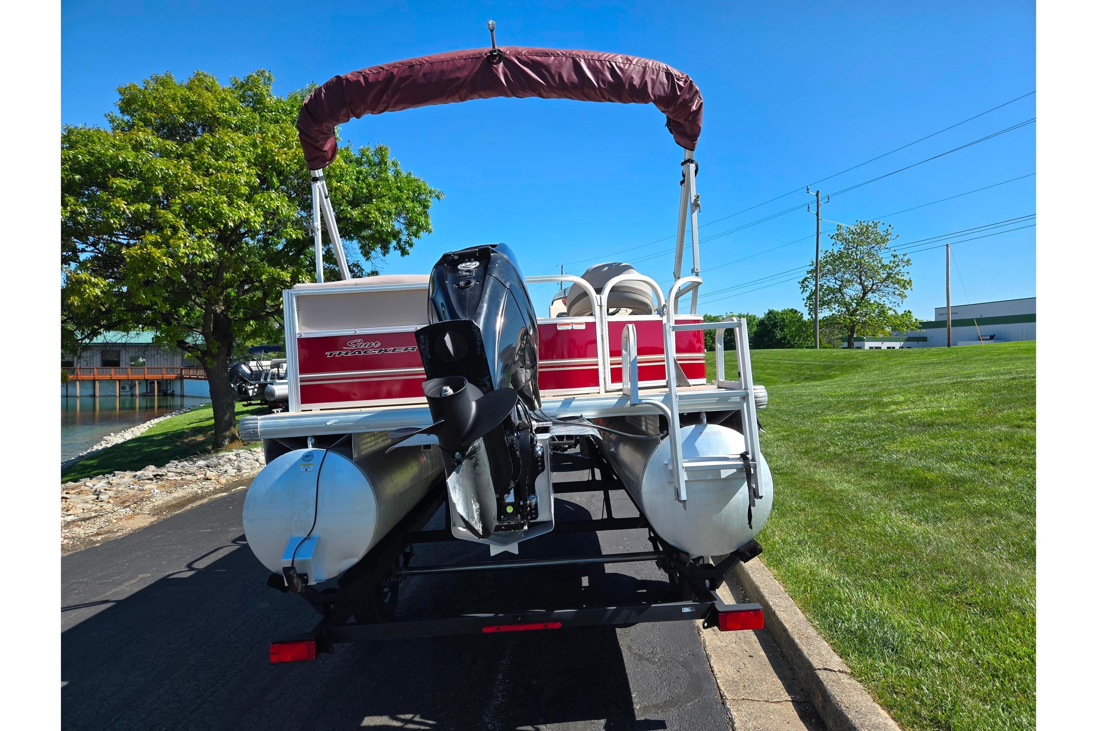2014 Sun Tracker Party Barge 20 DLX pontoon boat on trailer, parked near a lake.