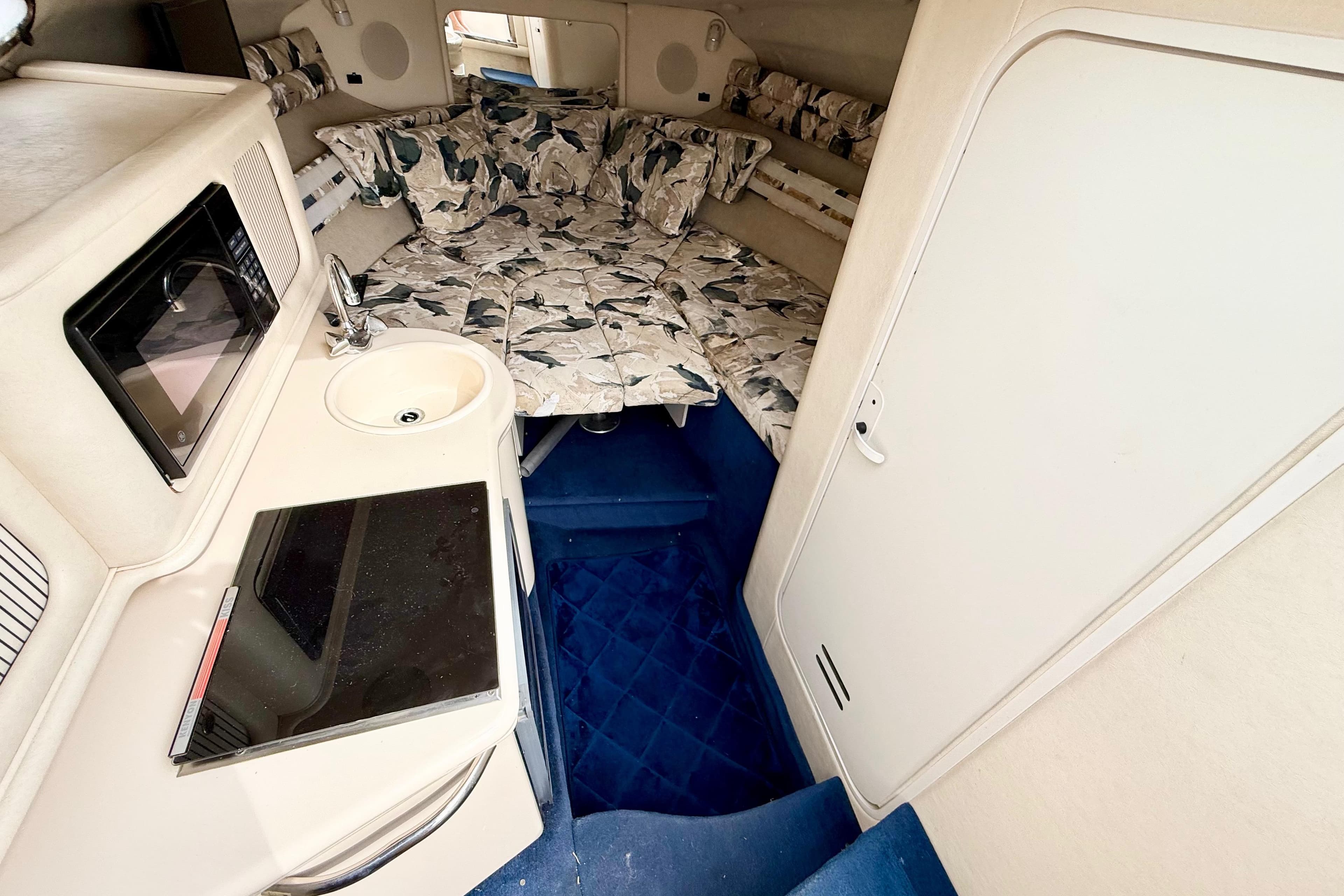Interior of 1999 Sea Ray Sundancer 260 with kitchenette and cozy sleeping area.