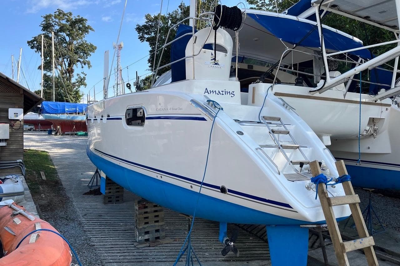 Catana 471 OCEAN CLASS 2004 catamaran on dry dock with blue accents and ladder.