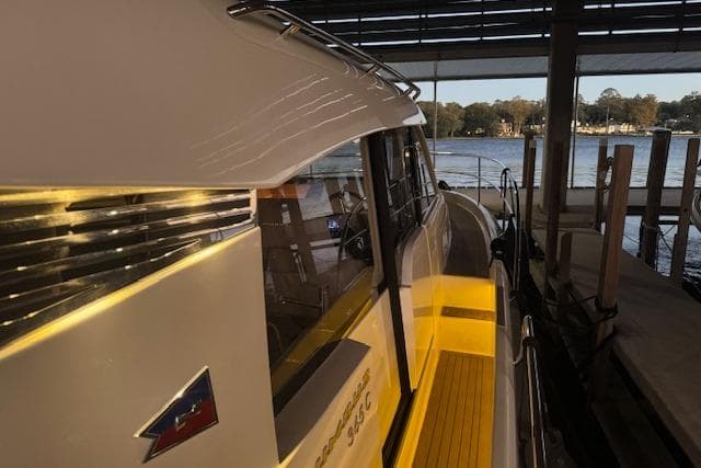 2022 Nimbus 365 Coupe docked, showcasing sleek design and illuminated deck at sunset.