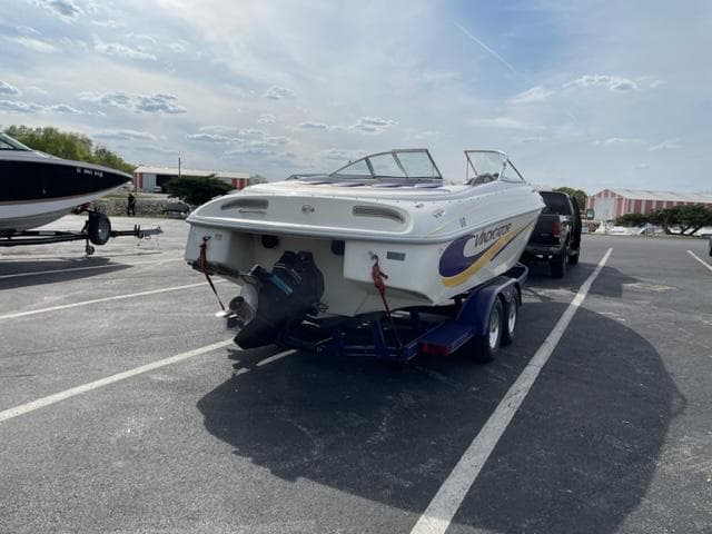 2002 VIP 2400 Vindicator boat on trailer in parking lot under cloudy sky.