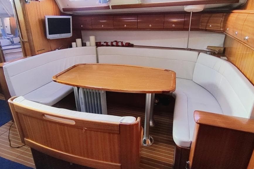 Interior of a 2003 Bavaria 49 yacht with a cozy dining area.