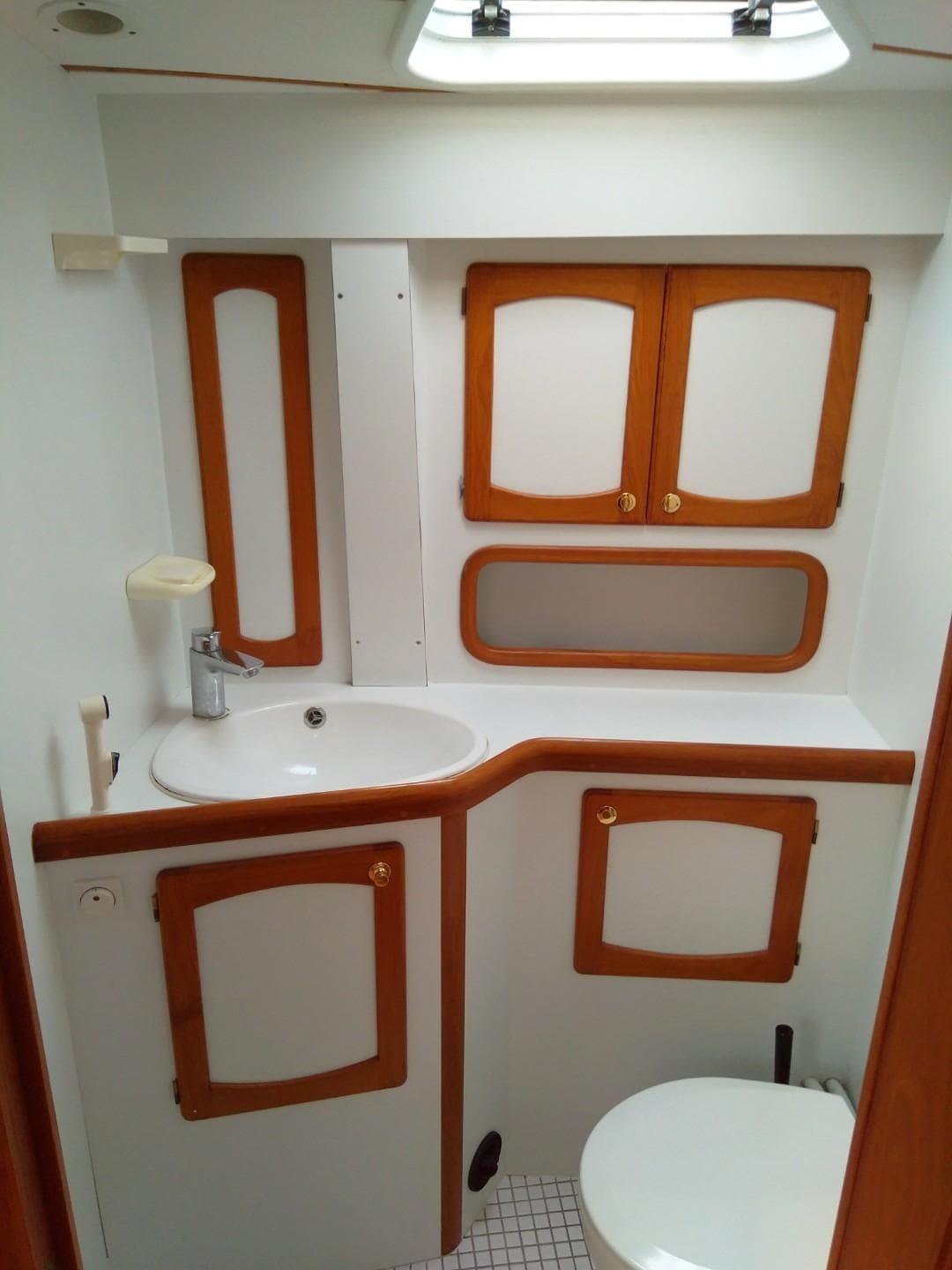 Nauticat 42 1996 yacht bathroom with wooden cabinets and white fixtures.