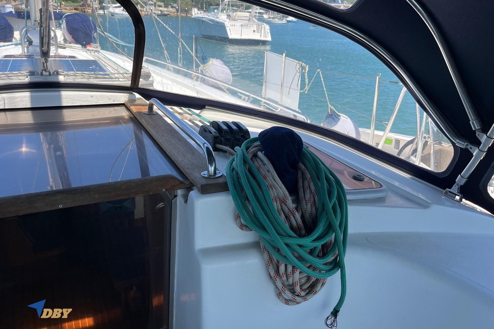 Cockpit view of a 2004 Bavaria 44 sailboat with coiled ropes and marina background.