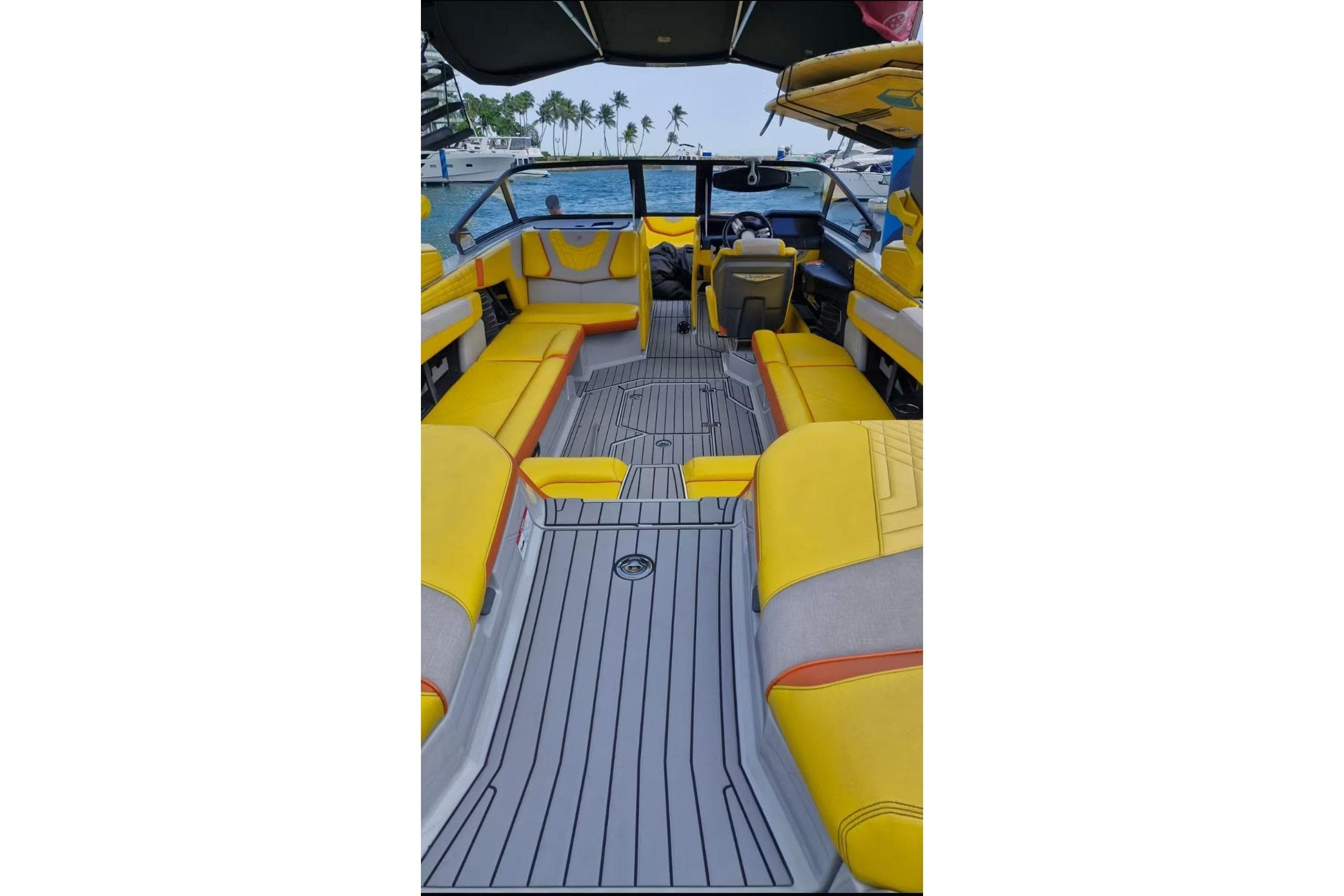 2022 Nautique Super Air Nautique G25 interior with yellow seating, ocean view, and palm trees.