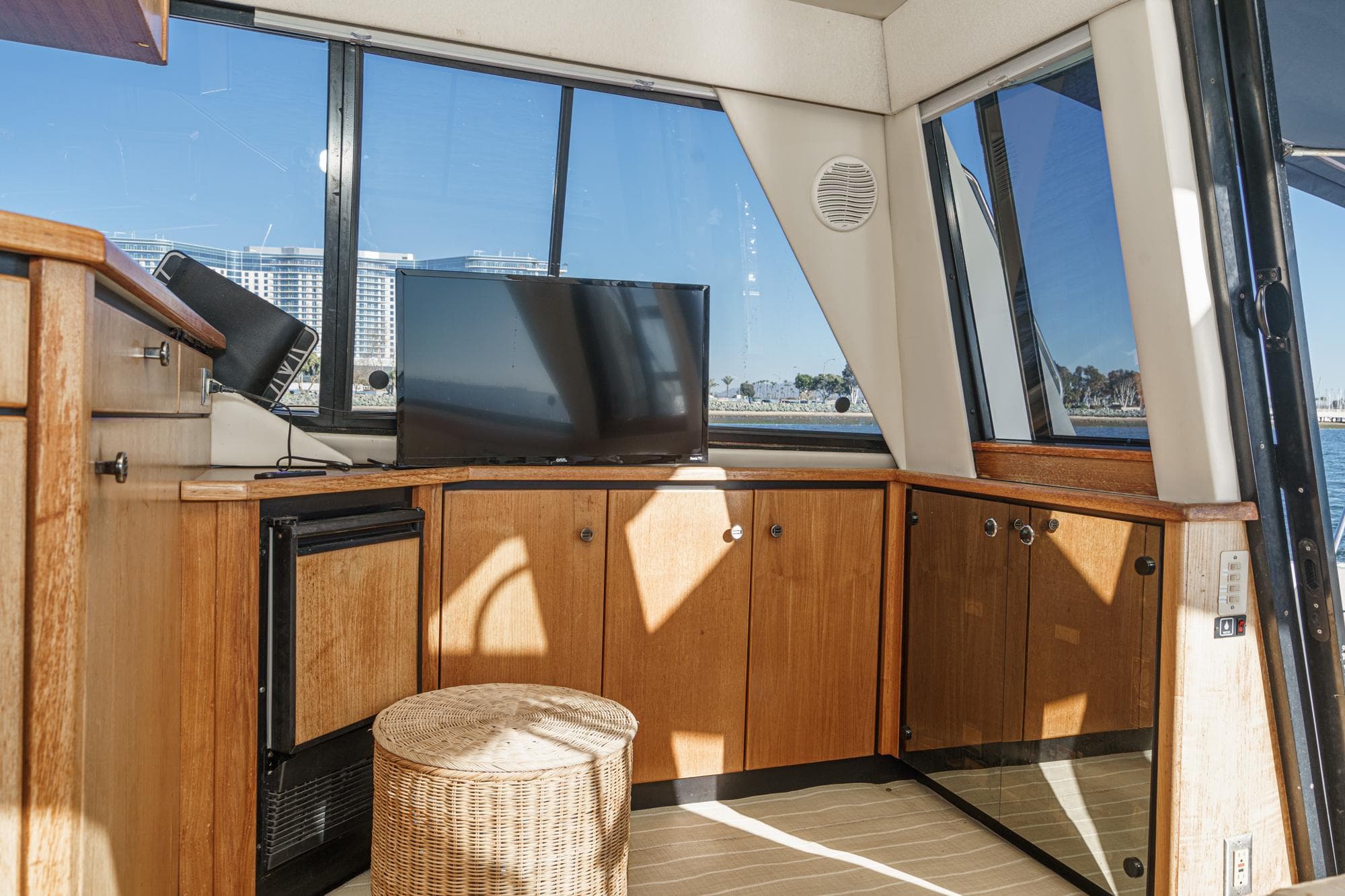 Interior of 1998 Bayliner 3988 Motoryacht with TV, wicker stool, and wooden cabinetry.