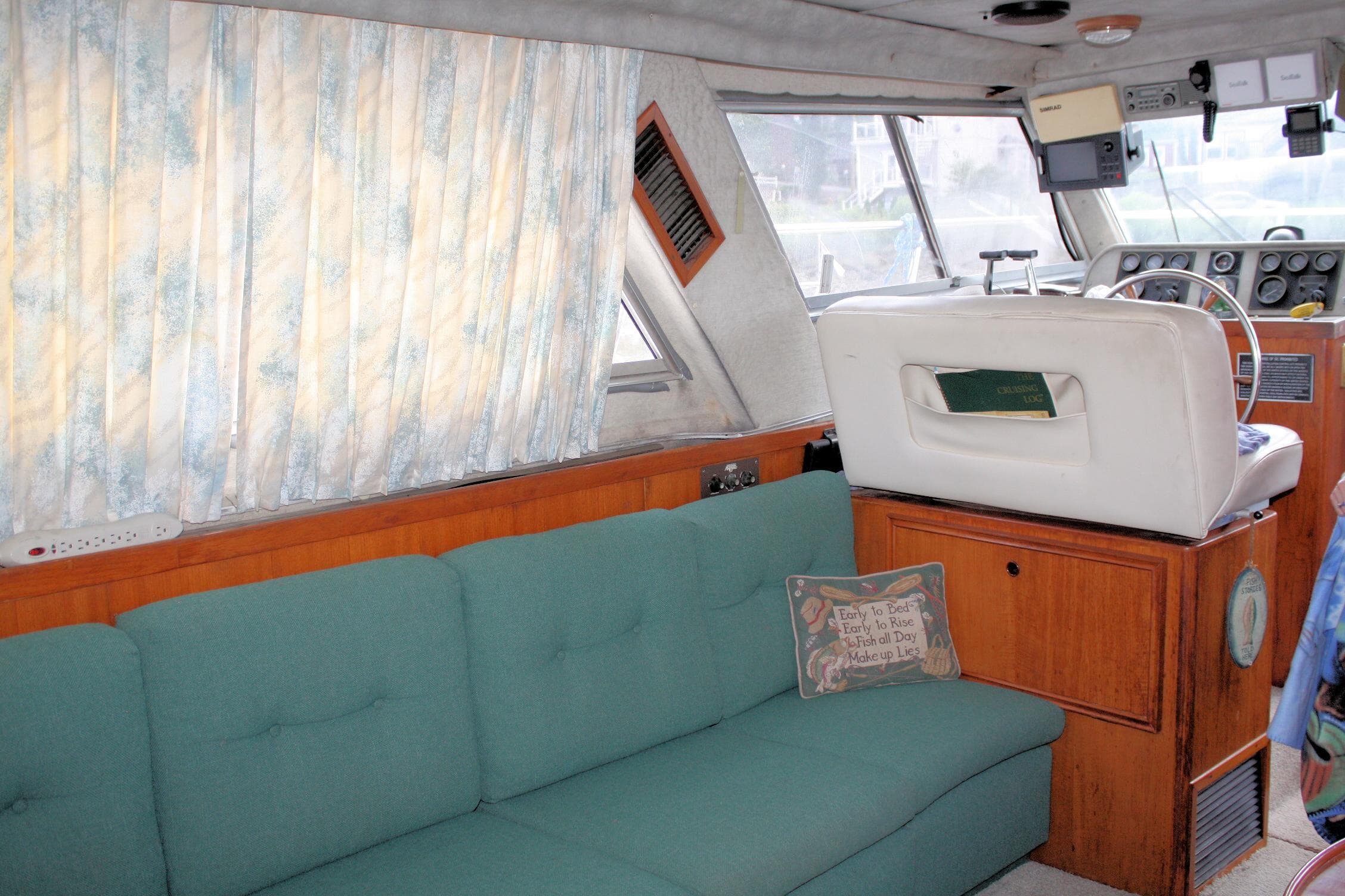 Interior of a 1986 Birchwood 42 Empress yacht with teal sofa and helm station.