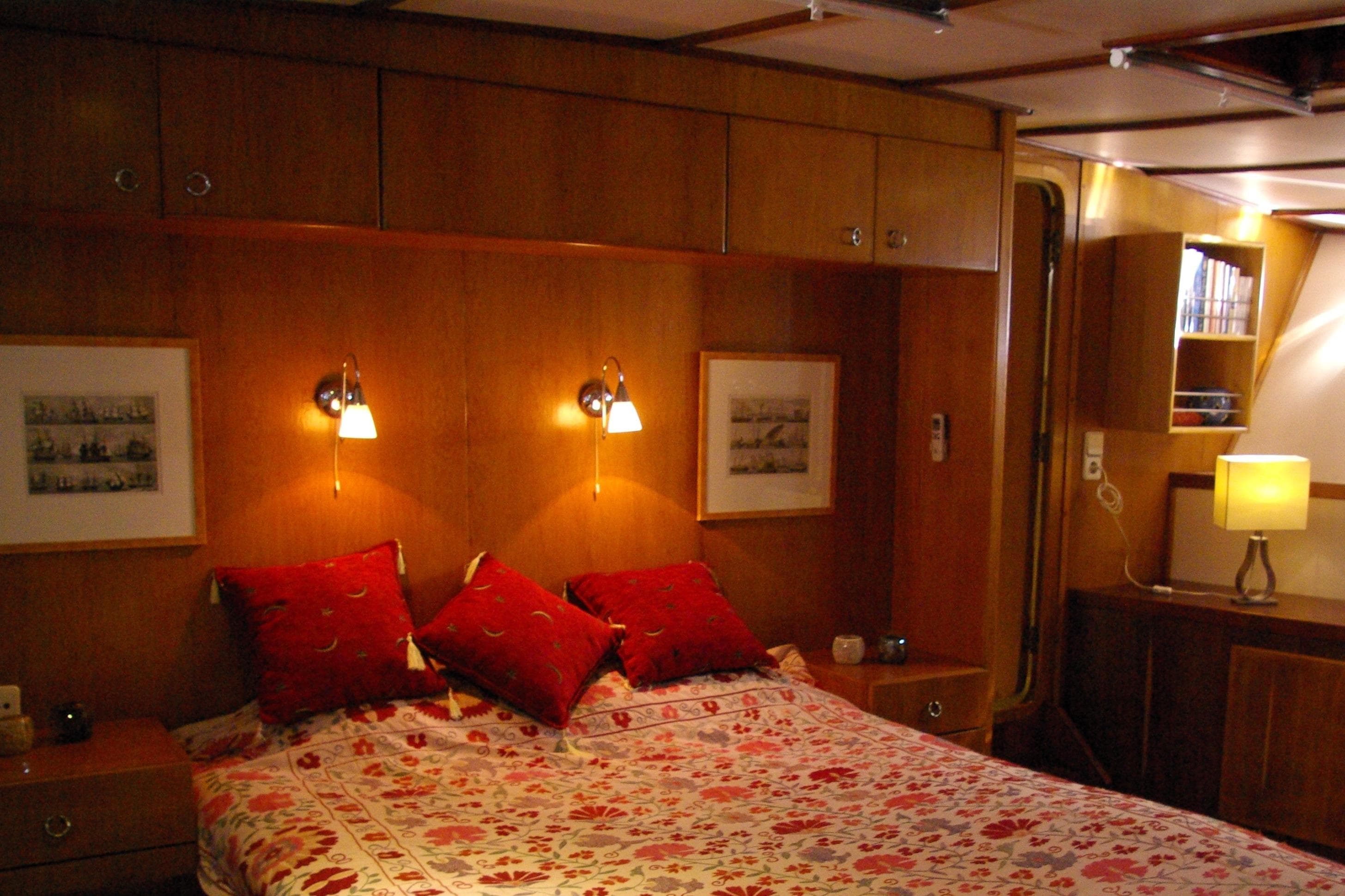 Luxurious 1992 Baymarin Custom yacht bedroom with elegant wood paneling and cozy lighting.
