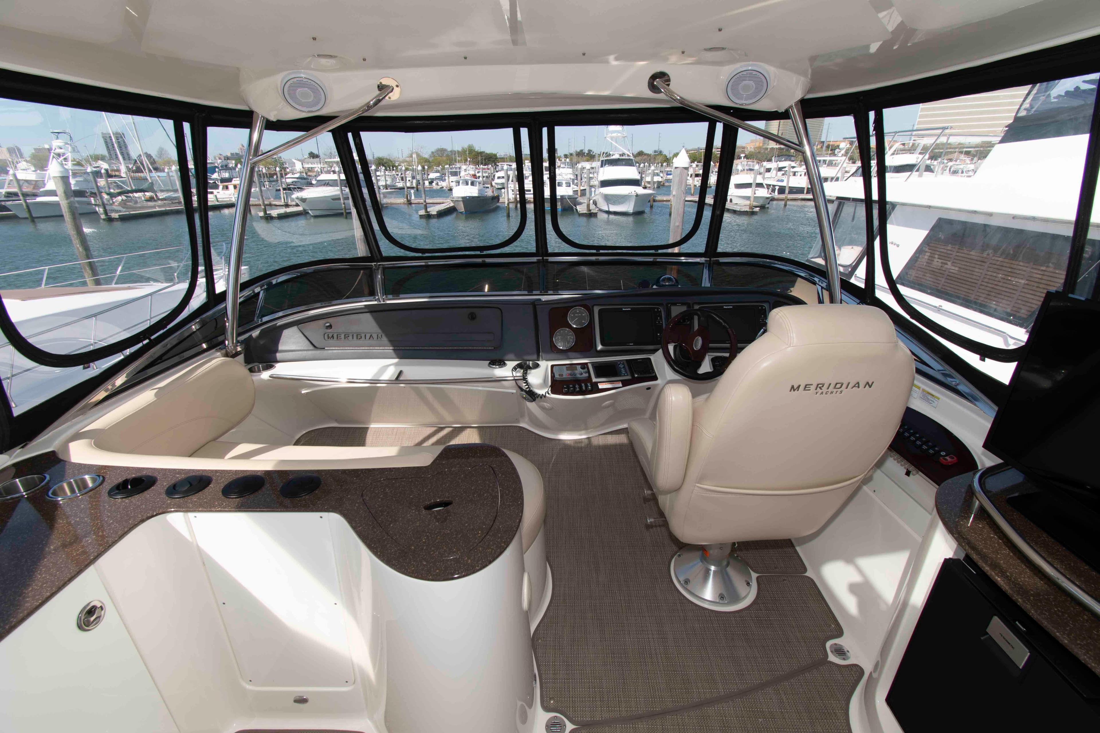 Interior view of 2013 Meridian 441 Sedan yacht cockpit with marina background.