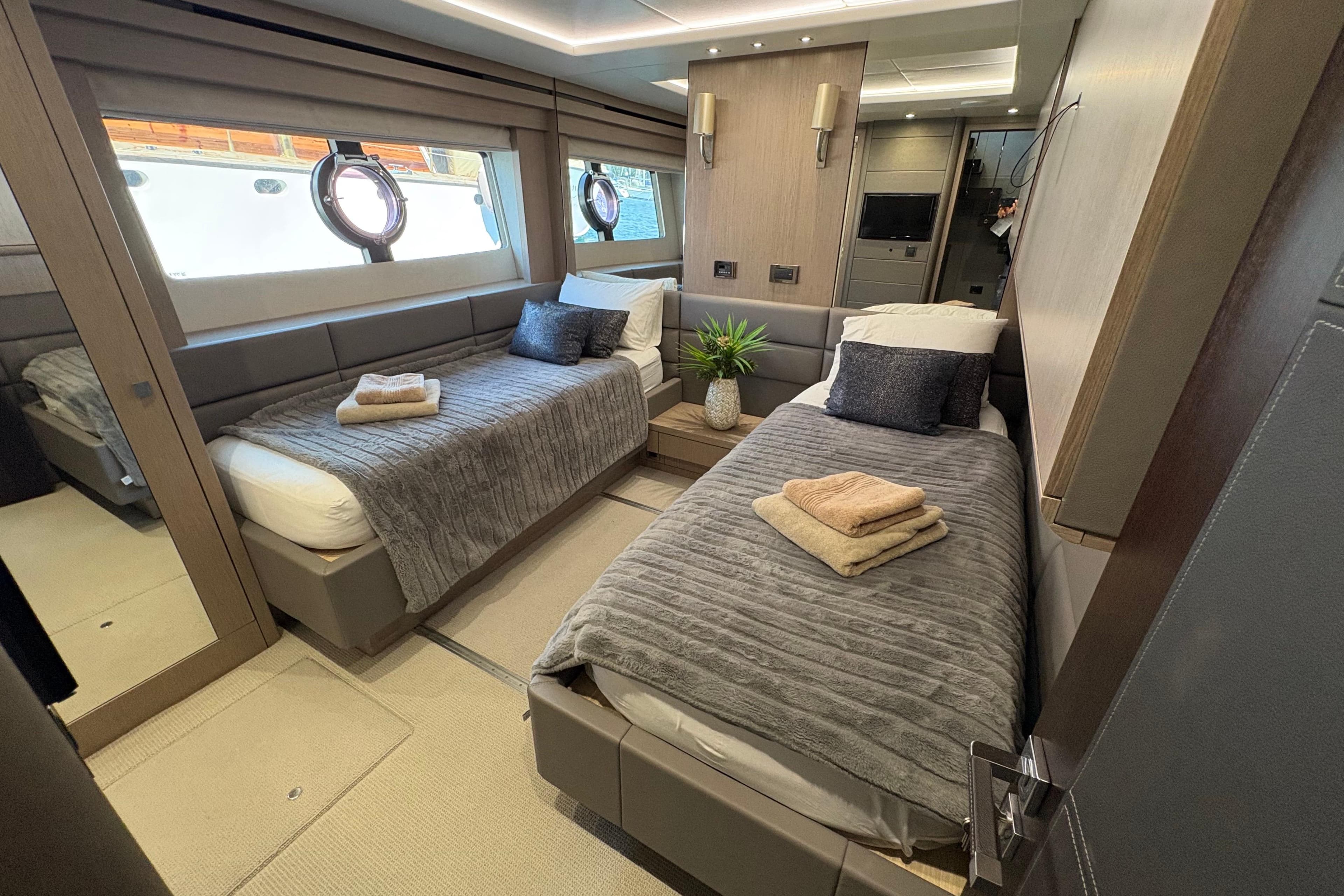 Luxurious twin bedroom on 2018 Sunseeker 86 Yacht, featuring modern decor and cozy bedding.