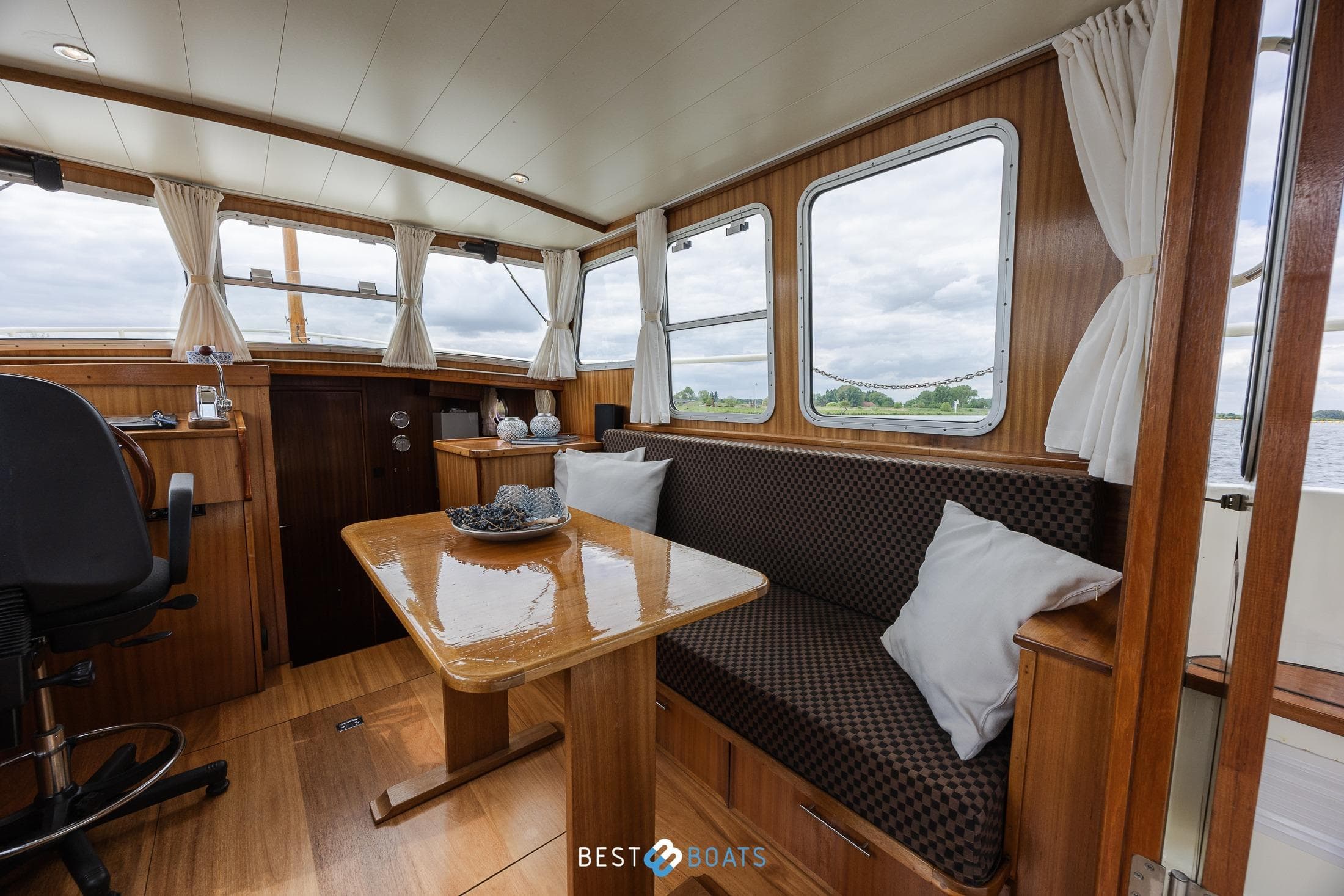 Interior of 2004 Vripack 965 OK boat with wooden furnishings and large windows.