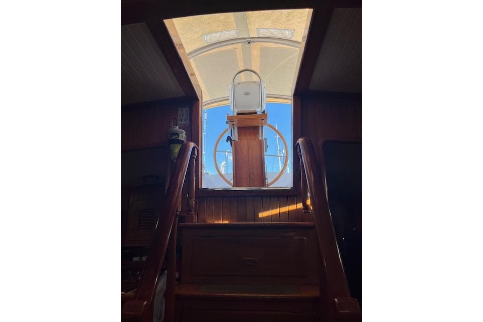 Interior view of 1986 Liberty 49 yacht, showcasing wooden stairs and helm station.