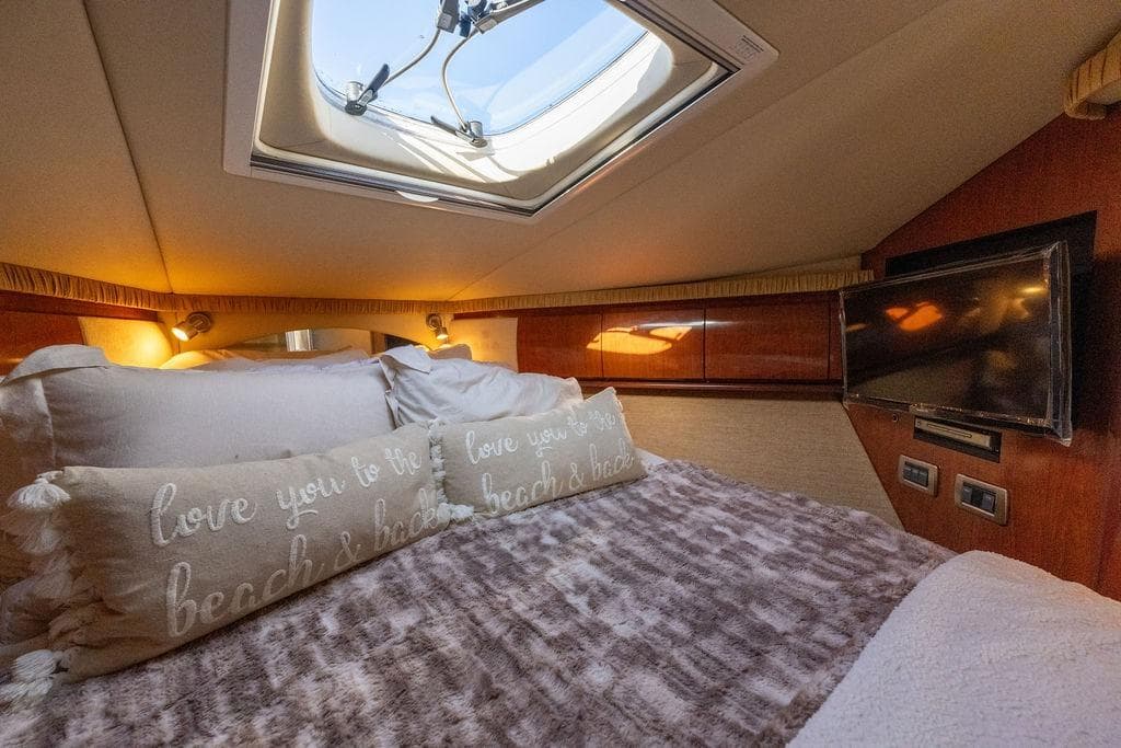 Luxurious cabin interior of 2005 Sea Ray 420 Sundancer with skylight and cozy bedding.