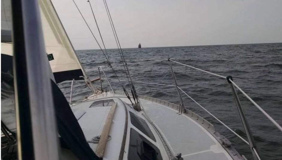 Sailing on a 1988 Hunter 30-2 yacht in open sea, distant lighthouse visible.