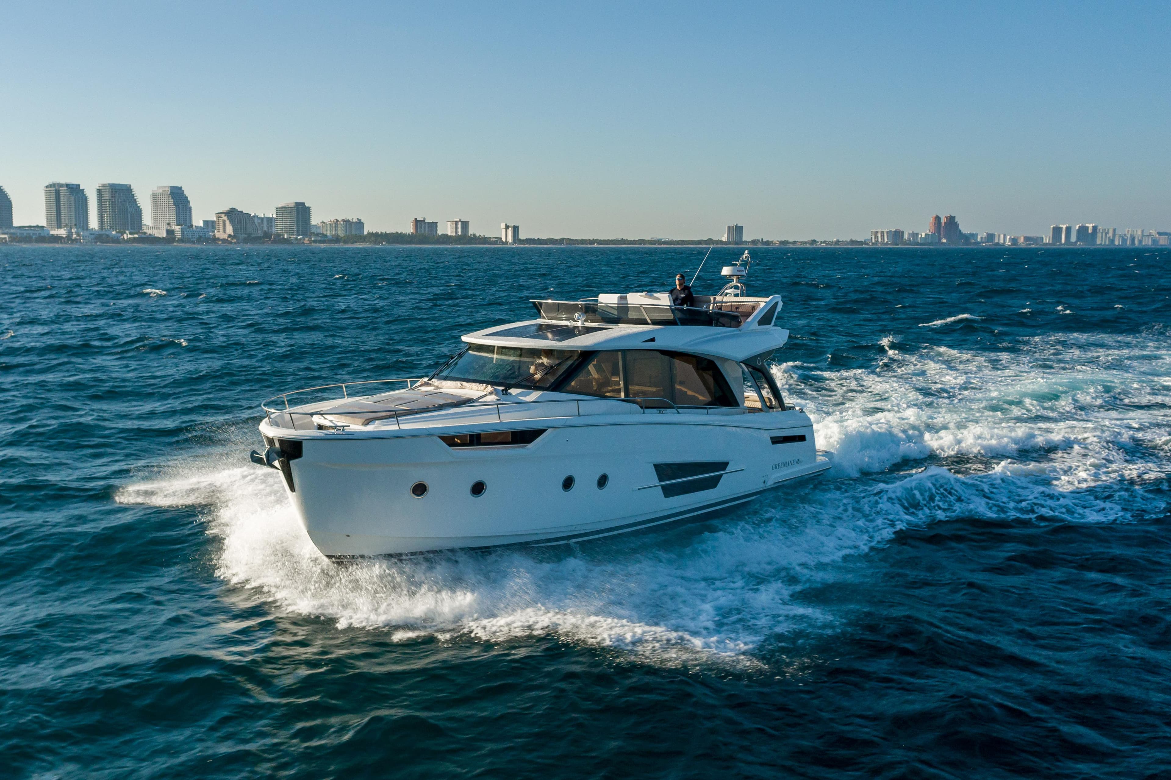 Greenline 45 Fly 2022 yacht cruising on open sea near city skyline.