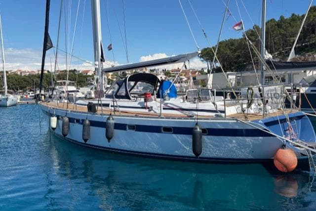 1984 Tayana 55 sailboat docked in a marina, surrounded by clear blue water.