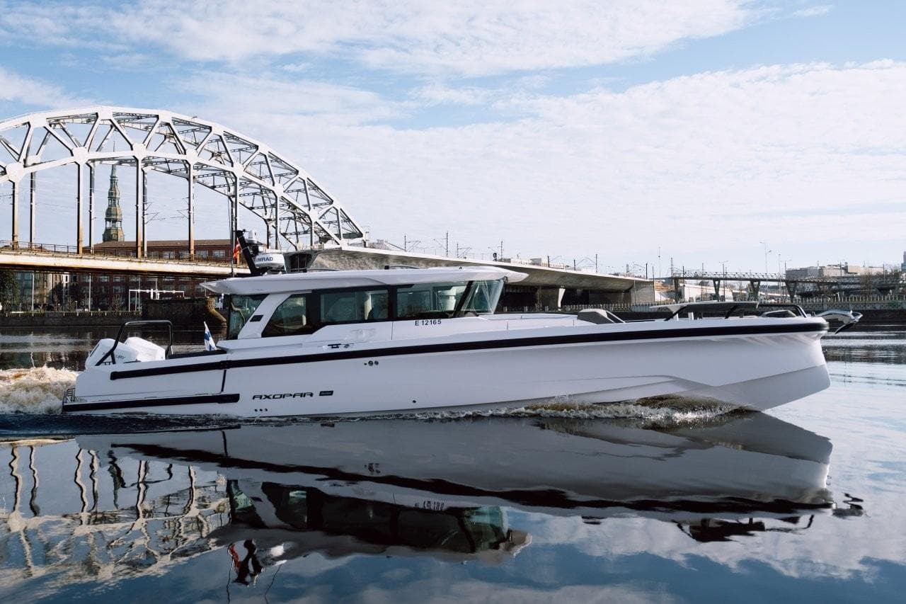 2026 Axopar 38 Cross Cabin boat cruising near a bridge on a calm river.