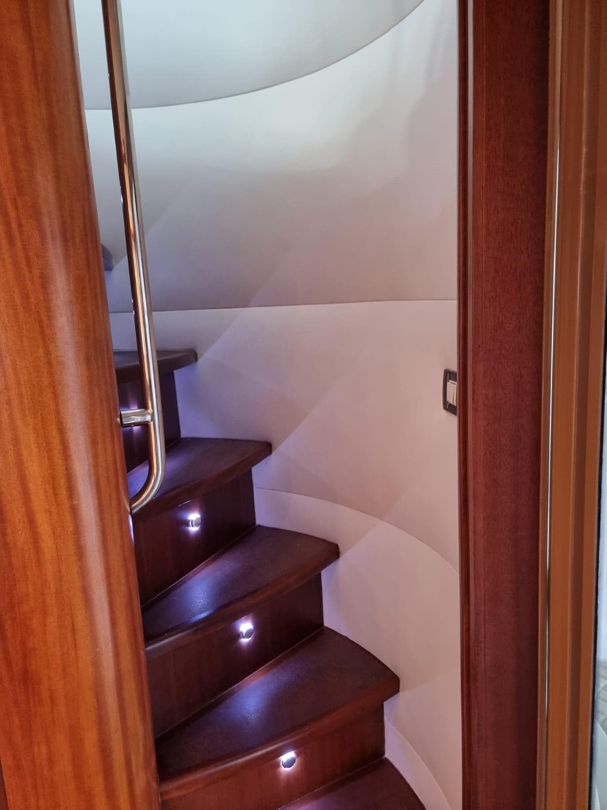 Interior staircase of 2009 Bertram 700 Enclosed yacht with wooden steps and LED lighting.