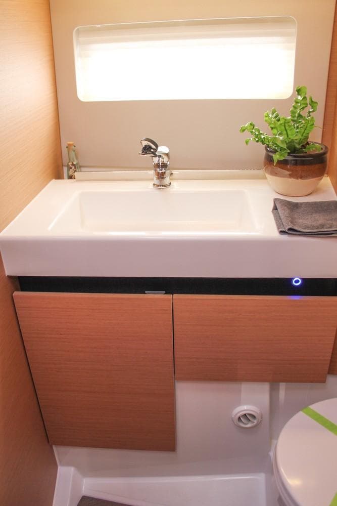 Modern bathroom in 2024 Jeanneau Sun Odyssey 490 yacht with sink and potted plant.