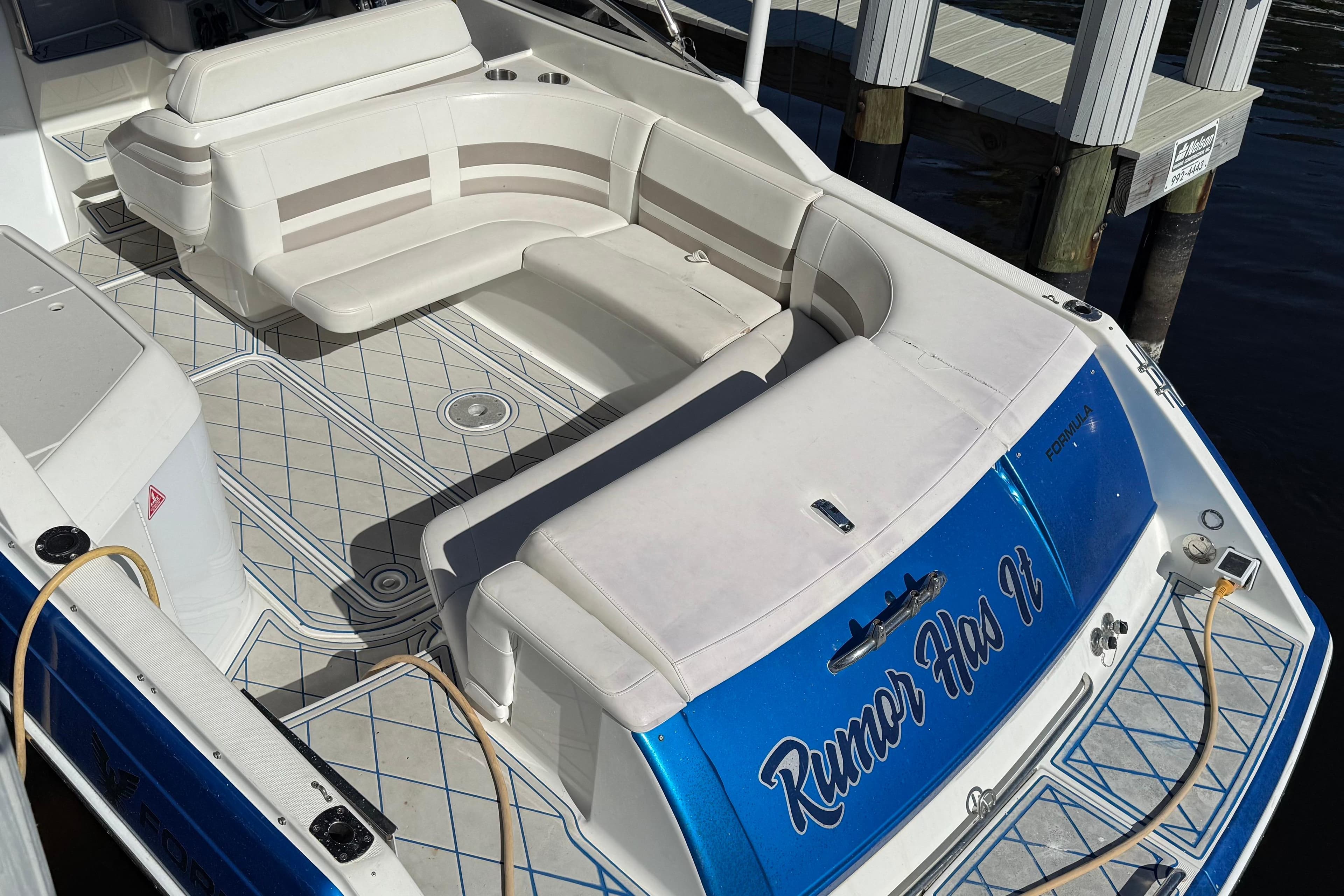 1999 Formula 280 Sun Sport boat with white seating and blue accents docked by the water.