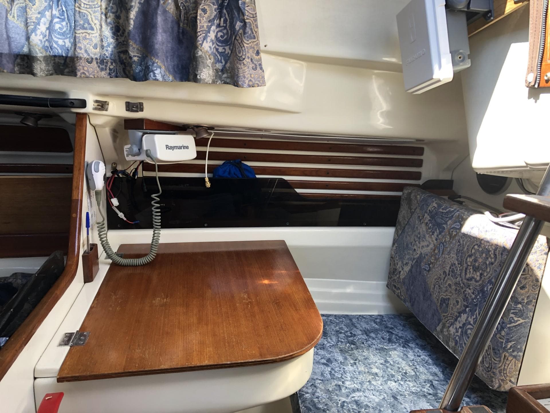 Interior of a 1980 Pearson 323 sailboat with wooden table and nautical equipment.
