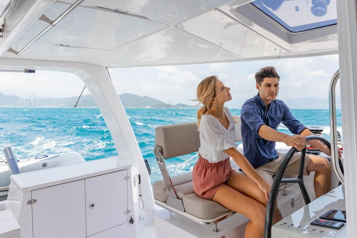 Couple enjoying a sail on a 2026 Seawind 1370 catamaran, with scenic ocean views.