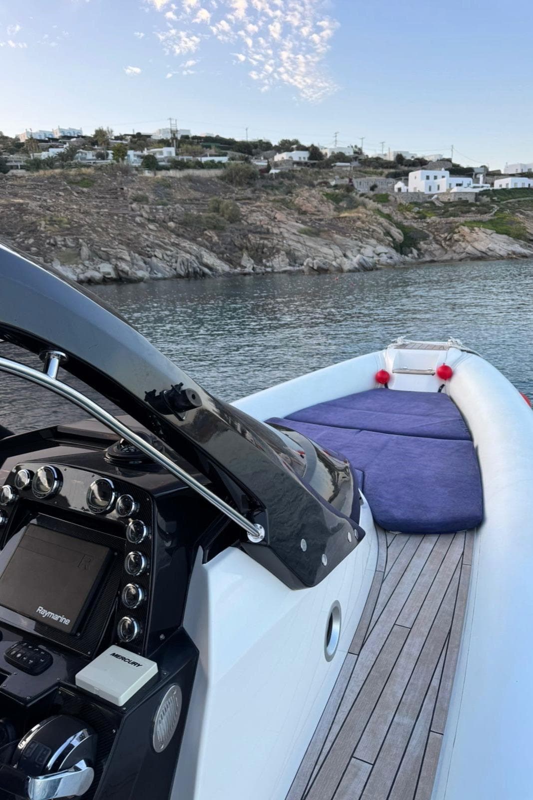 2016 SACS Strider 13 boat with sleek dashboard, wooden deck, and scenic coastal view.