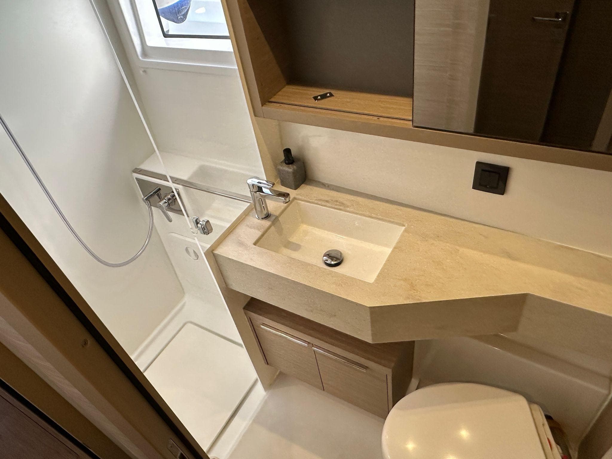 2024 Lagoon 46 yacht bathroom with modern sink, shower, and storage.