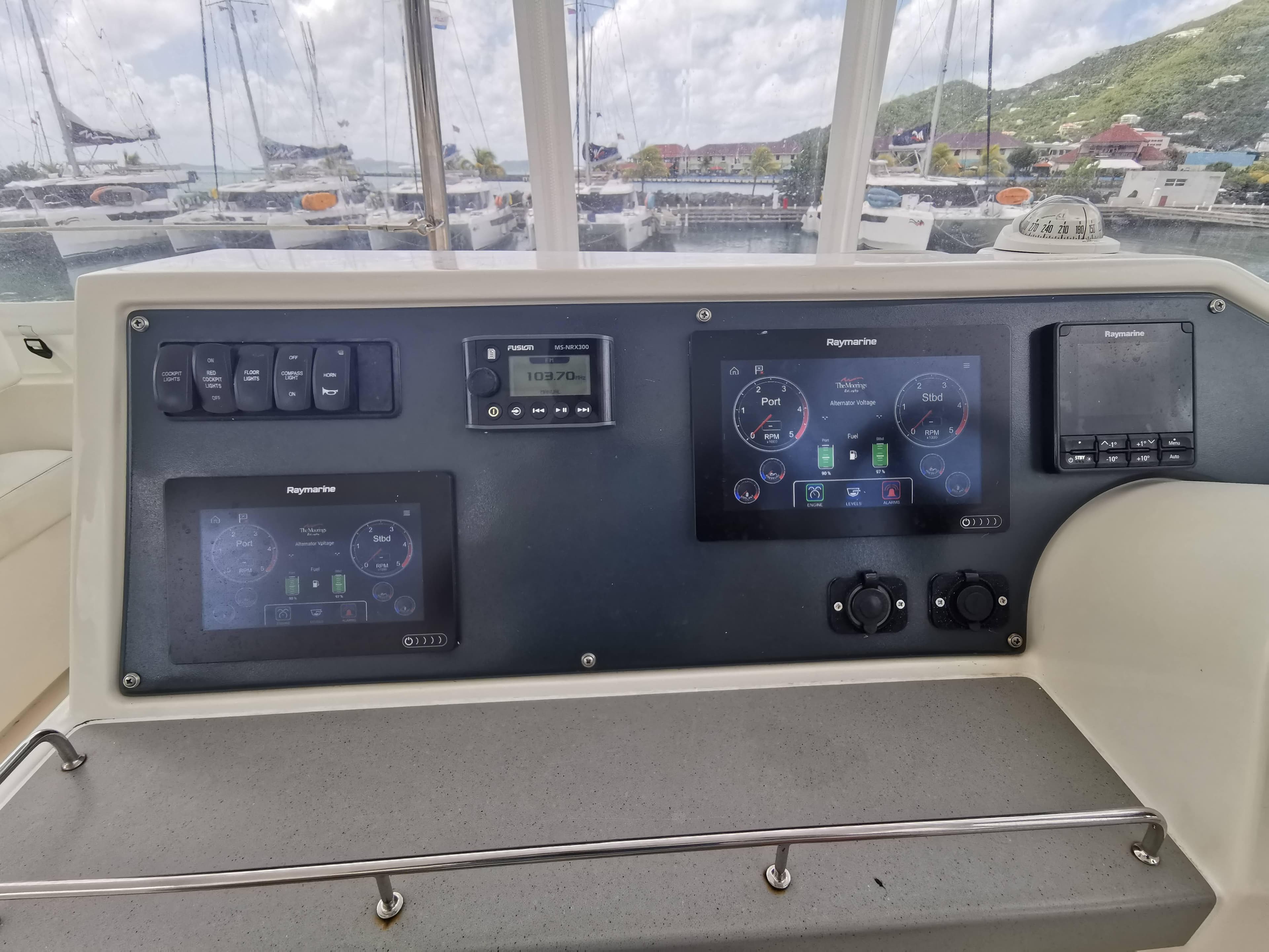Control panel of 2021 Leopard 43 Powercat with navigation screens and switches, docked in marina.
