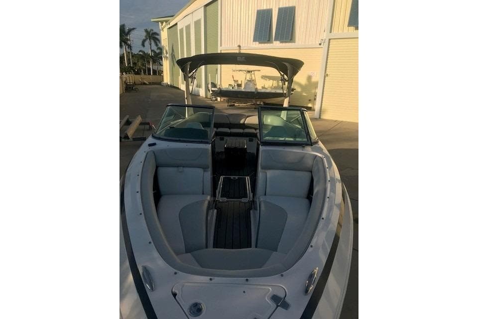 2012 Regal 2500 Bowrider boat with open seating, docked near a building.