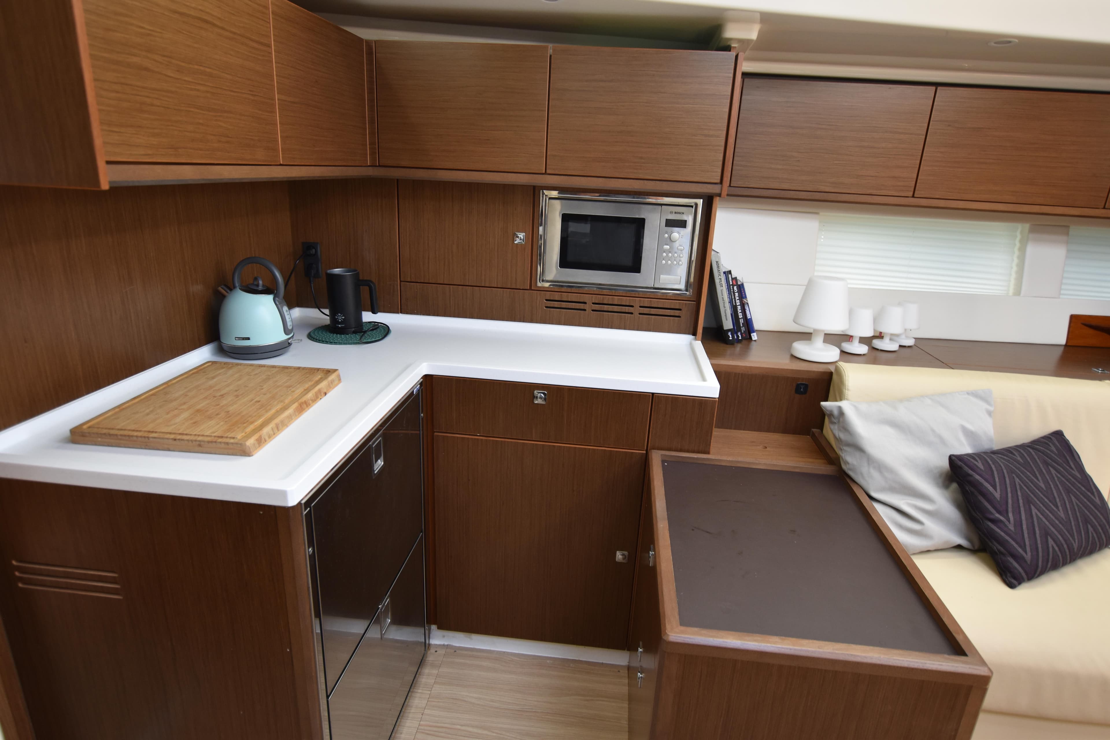 Modern kitchen interior of Luxury 2020 Bavaria C57 sailing yacht with wooden cabinetry and appliances.
