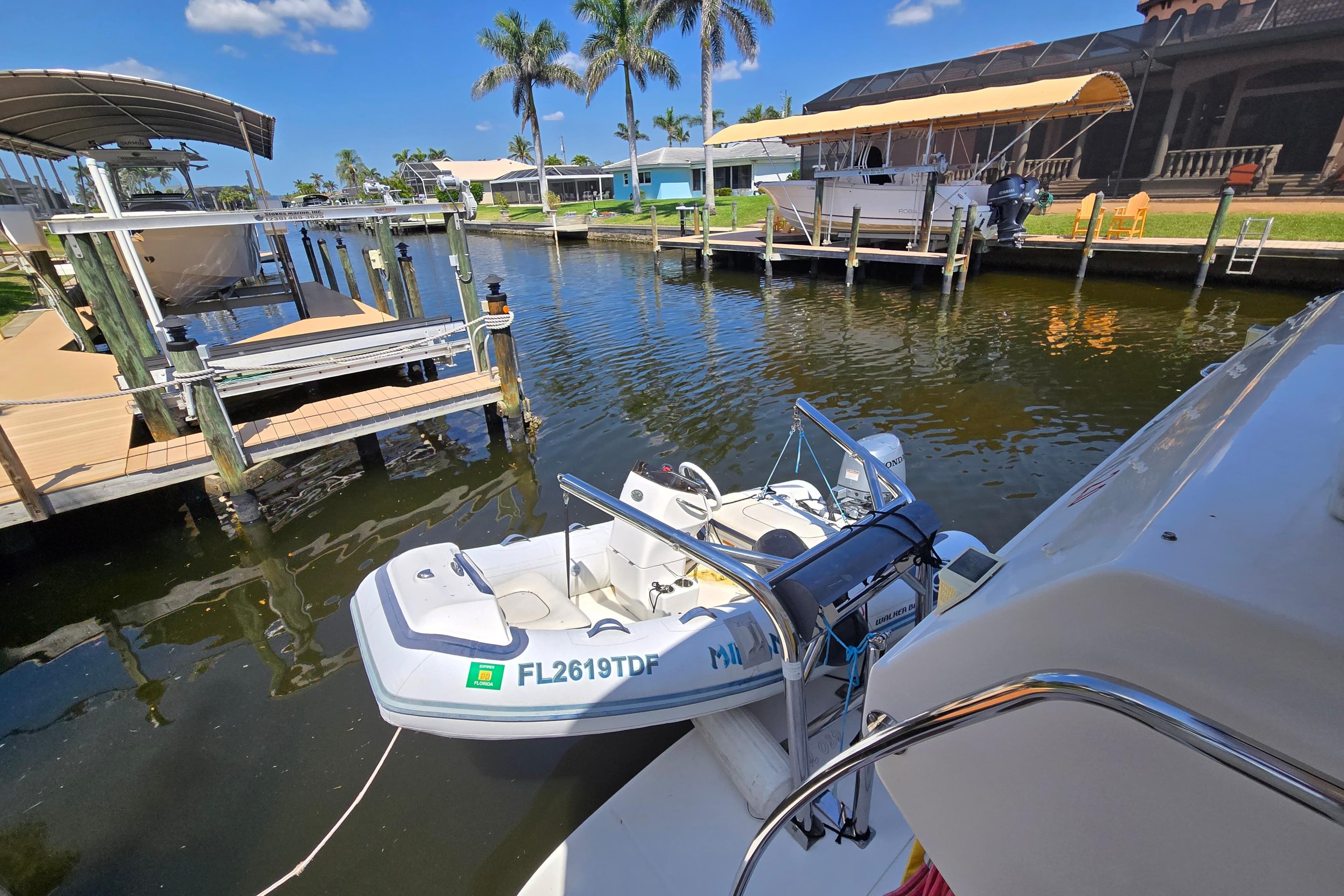 2004 Sea Ray 480 Motor Yacht docked with small boat, palm trees, and clear sky.