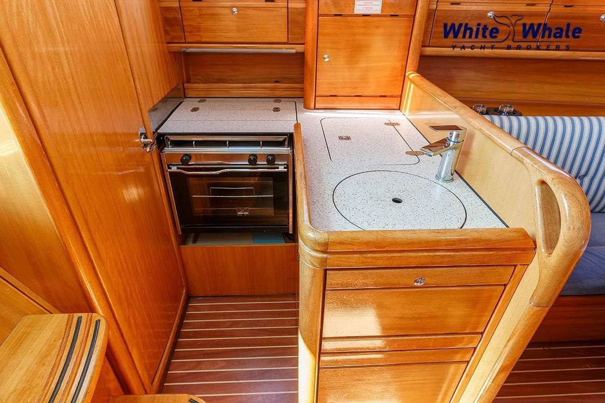 Interior of 2006 Bavaria Cruiser 30 yacht kitchen with wooden cabinetry and compact stove.