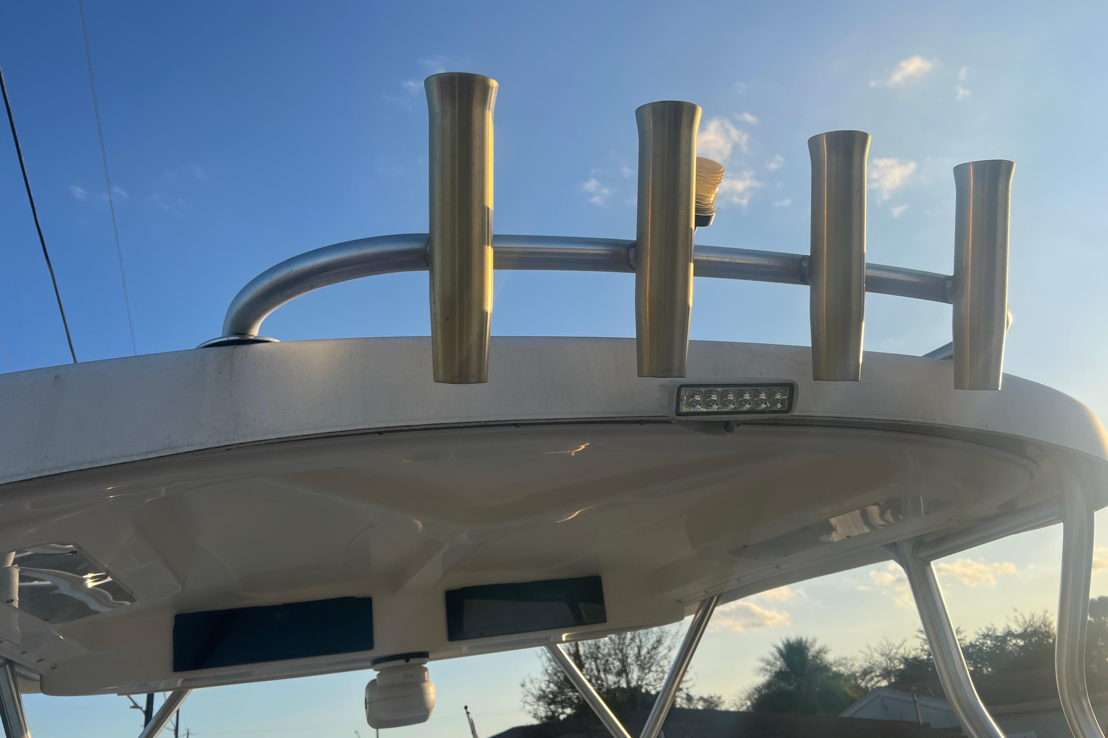 2011 Wellcraft 232 Coastal boat top with rod holders against a clear sky.