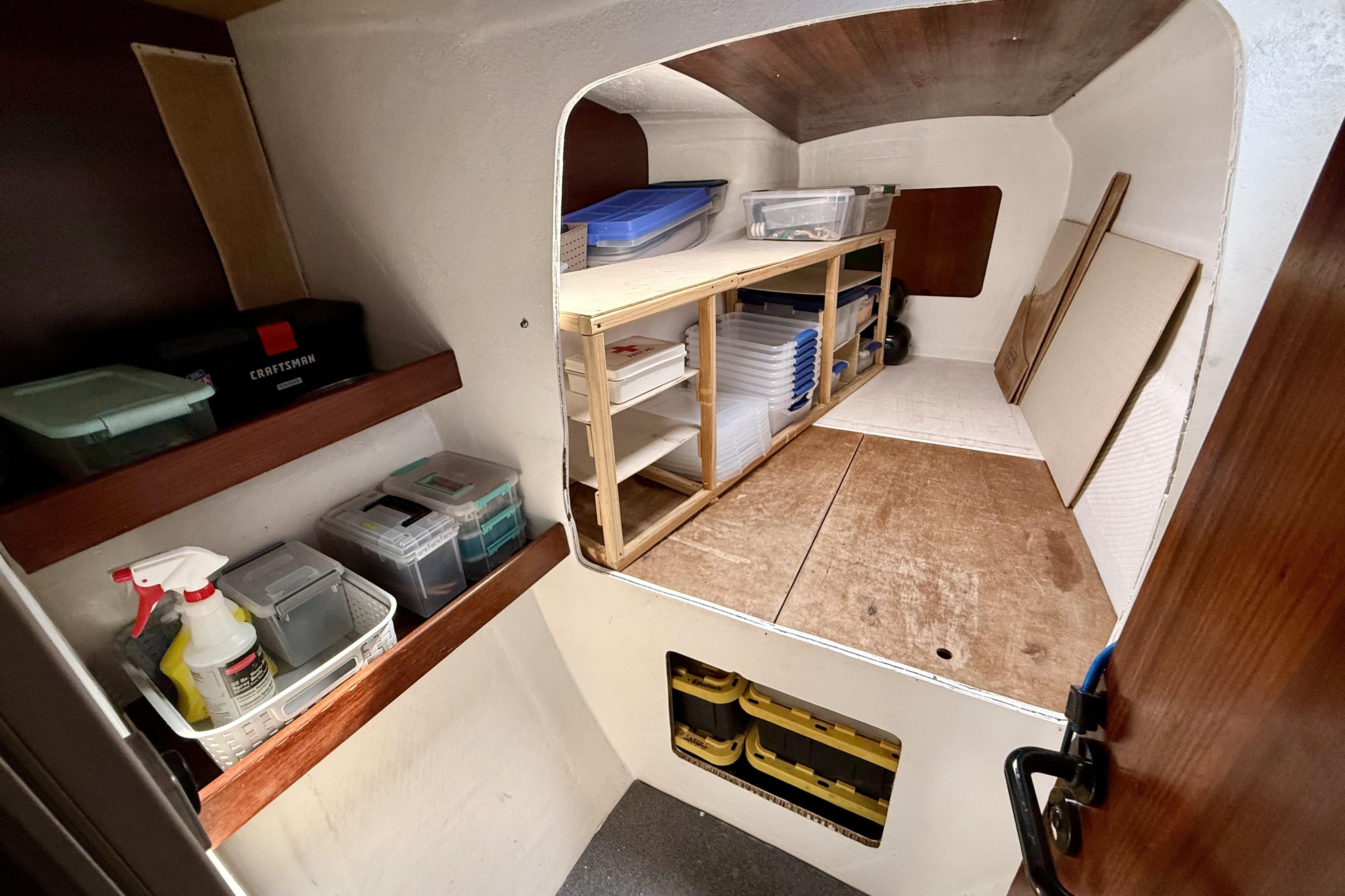 Storage area inside a 1995 Fountaine Pajot Athena 38 catamaran, featuring shelves and organized containers.