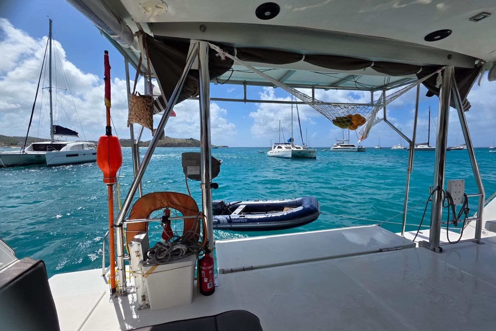 View from a 2016 Bali 4.5 catamaran, overlooking anchored boats in turquoise waters.