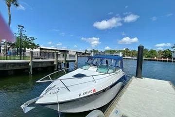 2000 Crownline 242 CR boat docked by a scenic waterfront under a clear blue sky.