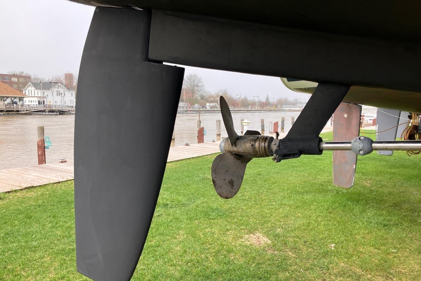 Propeller and rudder of a 1994 Sabre 362 sailboat on grassy shore.