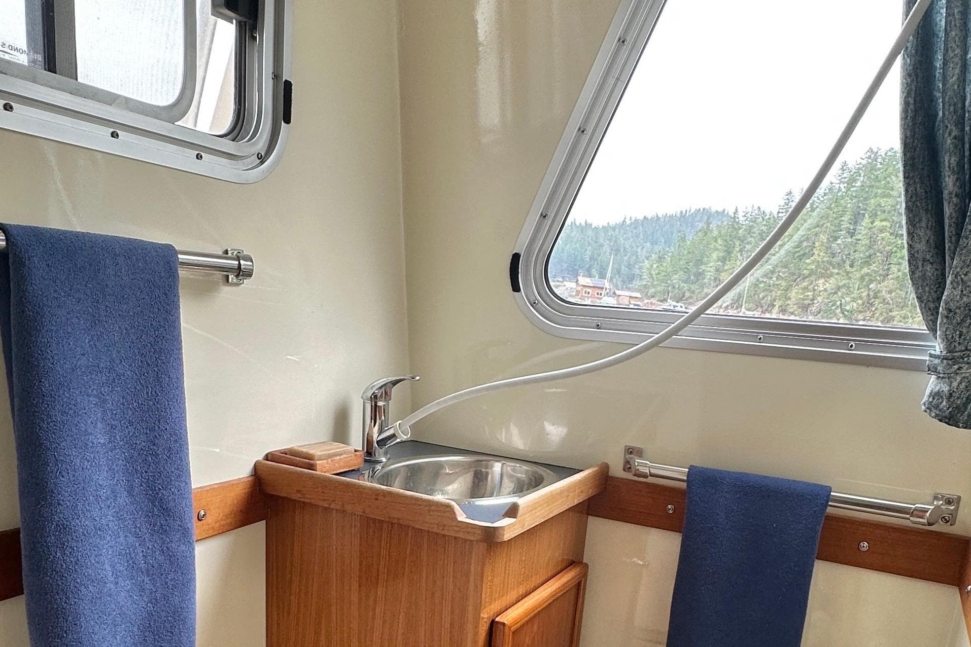 Interior of 2003 Coastal Craft 320 Cruiser with sink, window, and blue towels.